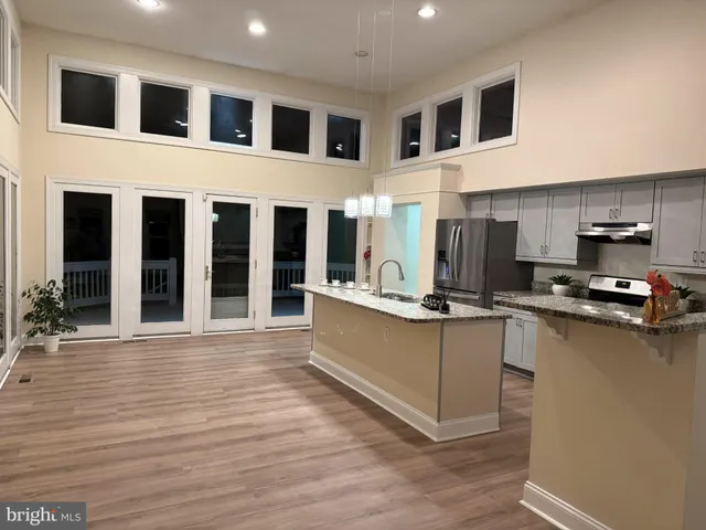 a kitchen with stainless steel appliances kitchen island granite countertop a stove a sink and a refrigerator