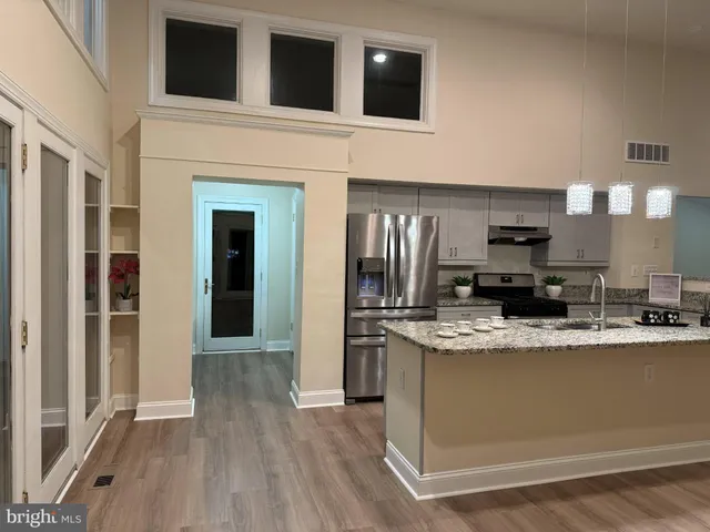 a large kitchen with kitchen island a stove a sink dishwasher and a refrigerator with wooden floor