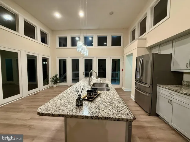 a large kitchen with kitchen island a stove a sink dishwasher and a refrigerator with wooden floor