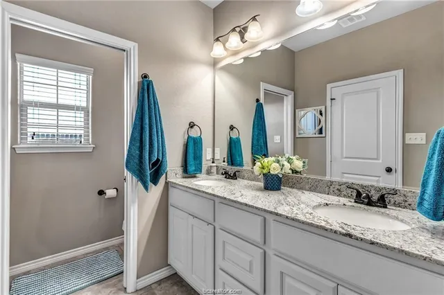 a bathroom with a granite countertop sink and a mirror
