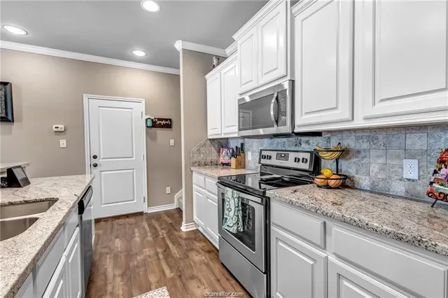 a kitchen with stainless steel appliances granite countertop a stove a sink and a refrigerator