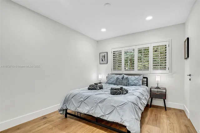 a bedroom with a bed and a window with wooden floor
