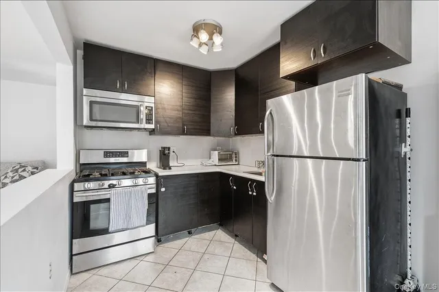 a kitchen with stainless steel appliances granite countertop a refrigerator a stove a sink and a microwave