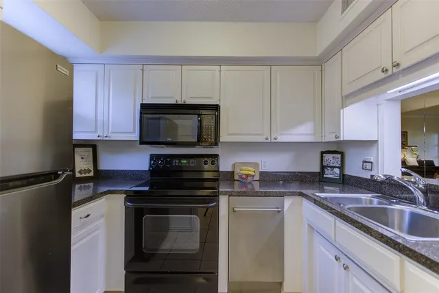 a kitchen with granite countertop white cabinets sink and stainless steel appliances