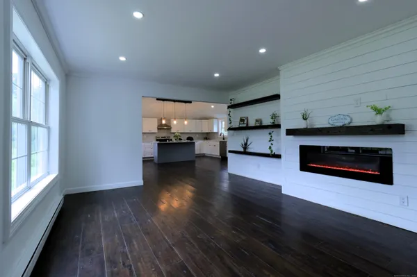 a living room with stainless steel appliances wooden floor and a kitchen view
