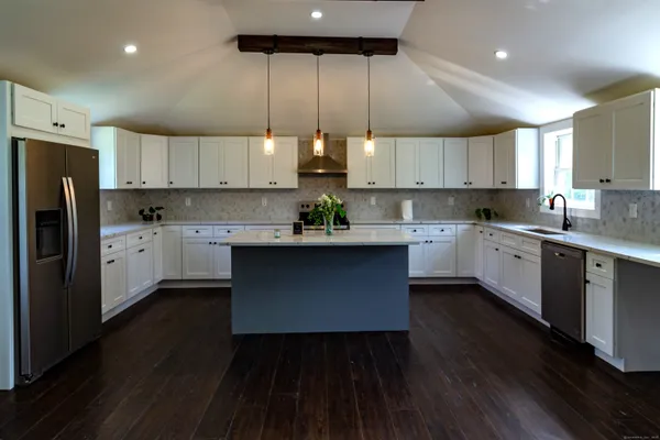 a kitchen with stainless steel appliances a refrigerator a sink dishwasher a stove and white cabinets with wooden floor