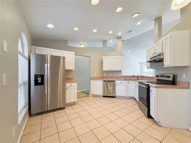a large kitchen with stainless steel appliances lots of white cabinets