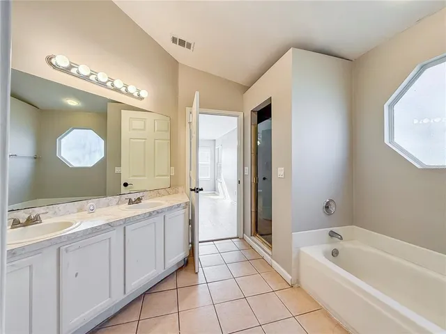 a spacious bathroom with a double vanity sink mirror and bathtub
