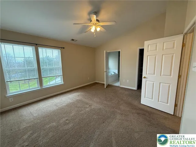 an empty room with windows and ceiling fan