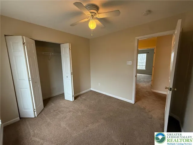 an empty room with closet and a chandelier fan