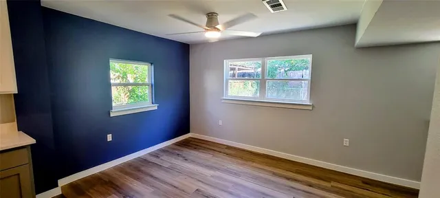 a view of empty room with wooden floor and fan