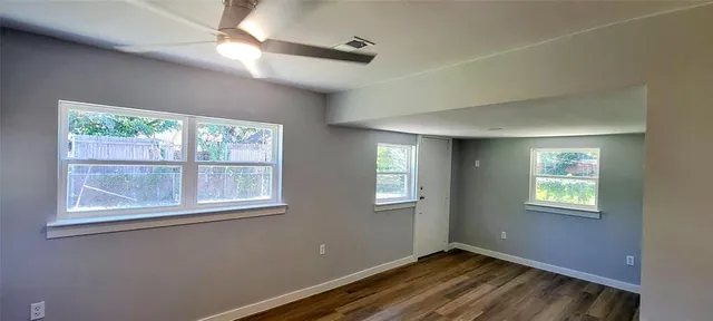 a view of an empty room with a window and wooden floor