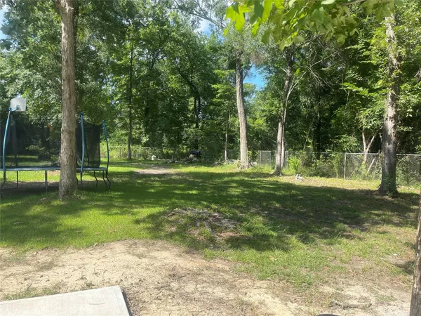 a backyard of a house with basket ball court and trees