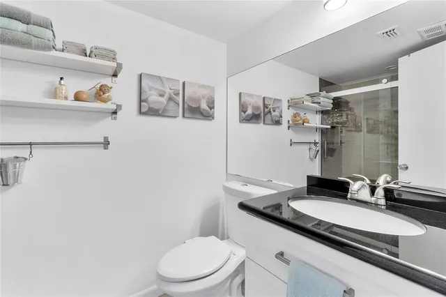 a bathroom with a granite countertop sink a toilet and a mirror