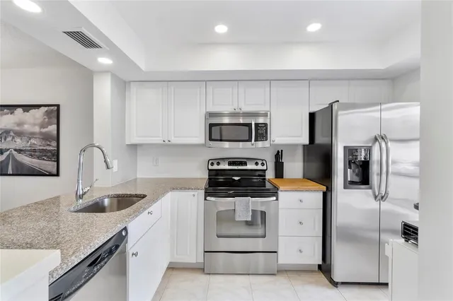 a kitchen with stainless steel appliances granite countertop a stove a sink and a refrigerator