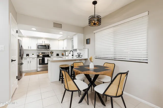 a dining room with stainless steel appliances kitchen island granite countertop a dining table chairs and a refrigerator