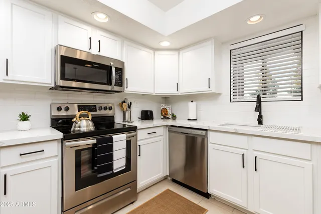 a kitchen with white cabinets and appliances