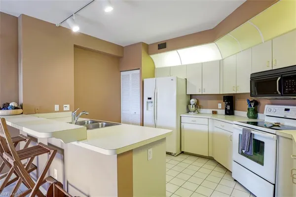 a kitchen with a sink a stove a refrigerator and white cabinets