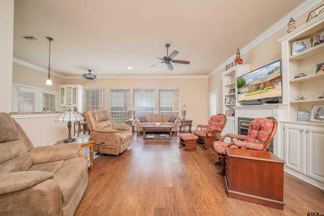 a living room with furniture kitchen view and a wooden floor