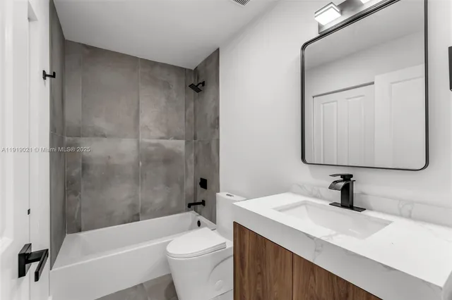 a bathroom with a sink a toilet a mirror a bathtub and shower