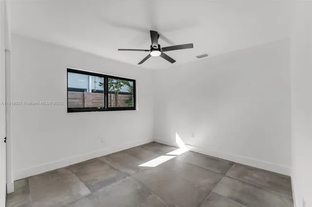 an empty room with windows and fan