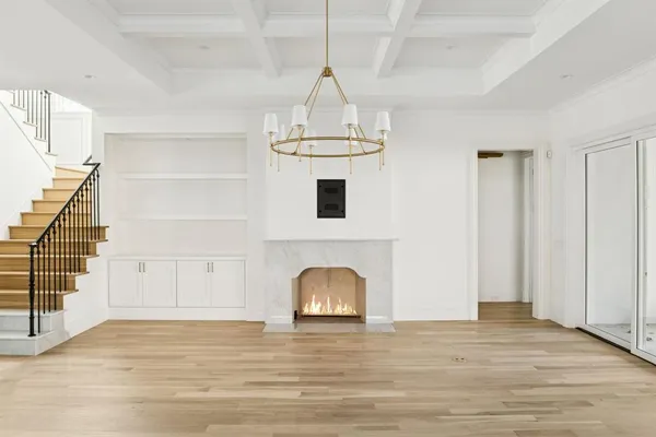 a view of a livingroom with wooden floor staircase and a kitchen space