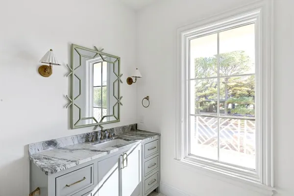 a bathroom with a granite countertop sink and a window