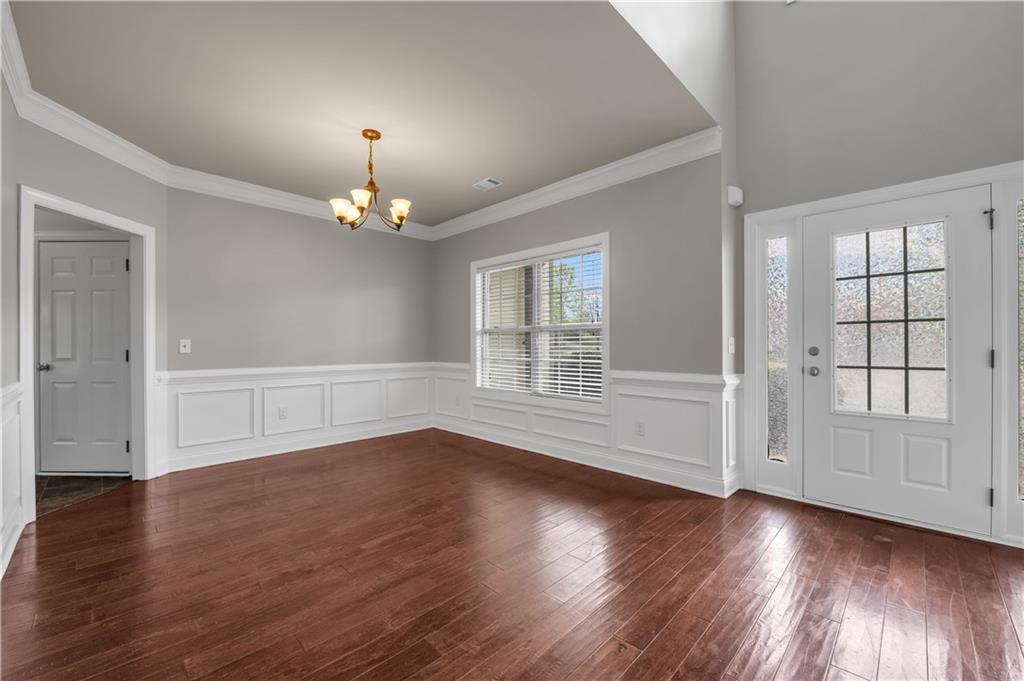 2626 Holden Spring Drive Dacula, GA 30019 - Photo 14 of 62 an empty room with wooden floor chandelier and windows