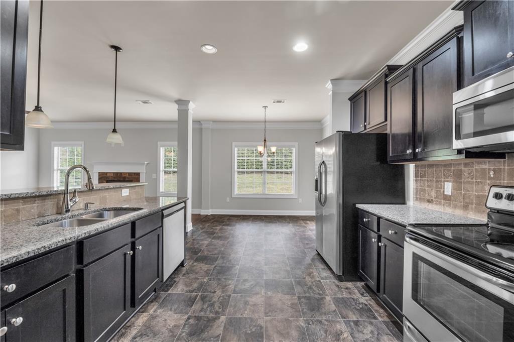 2626 Holden Spring Drive Dacula, GA 30019 - Photo 28 of 62 a kitchen with stainless steel appliances granite countertop a refrigerator a sink a stove a microwave and wooden cabinets