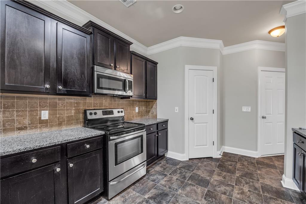2626 Holden Spring Drive Dacula, GA 30019 - Photo 32 of 62 a kitchen with granite countertop wooden cabinets and a stove top oven