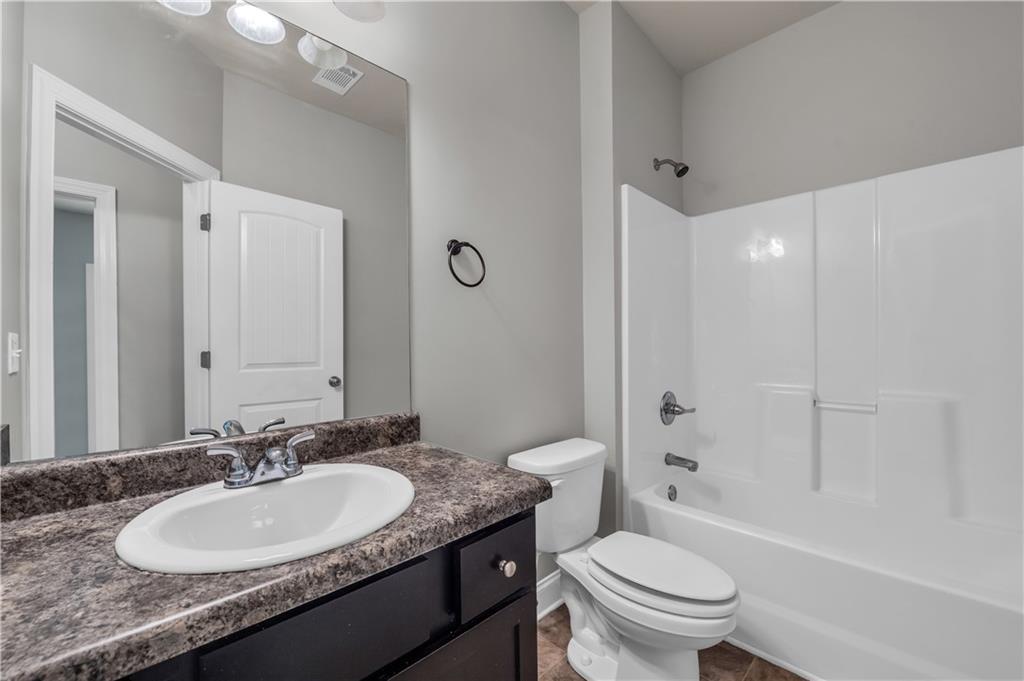 2626 Holden Spring Drive Dacula, GA 30019 - Photo 37 of 62 a bathroom with a granite countertop sink toilet a mirror and shower