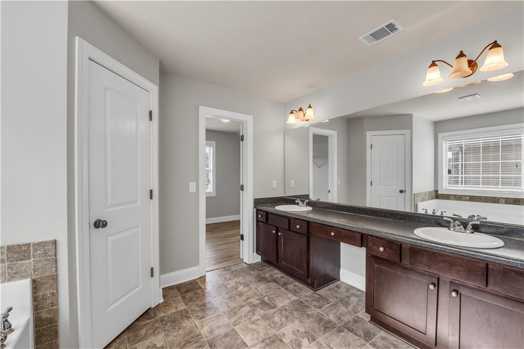 2626 Holden Spring Drive Dacula, GA 30019 - Photo 52 of 62 a spacious bathroom with a granite countertop sink a mirror and a shower