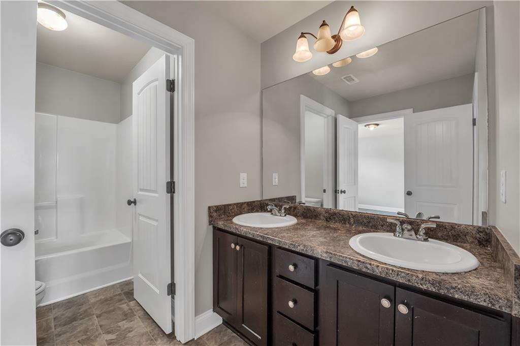 2626 Holden Spring Drive Dacula, GA 30019 - Photo 61 of 62 a bathroom with a granite countertop sink a large mirror and a bathtub