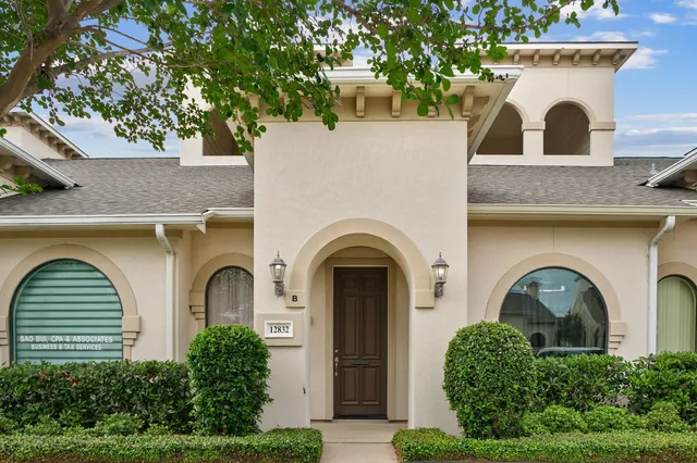 a view of a grey house with large windows and a small yard