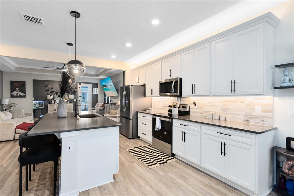 6528 Rover Way St. Cloud, FL 34771 - Photo 2 of 26 a kitchen with stainless steel appliances kitchen island granite countertop a sink stove and white cabinets with wooden floor
