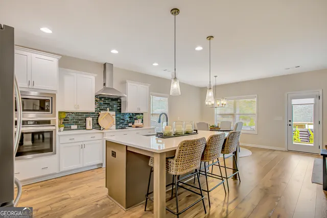 a kitchen with stainless steel appliances granite countertop a dining table chairs refrigerator and microwave