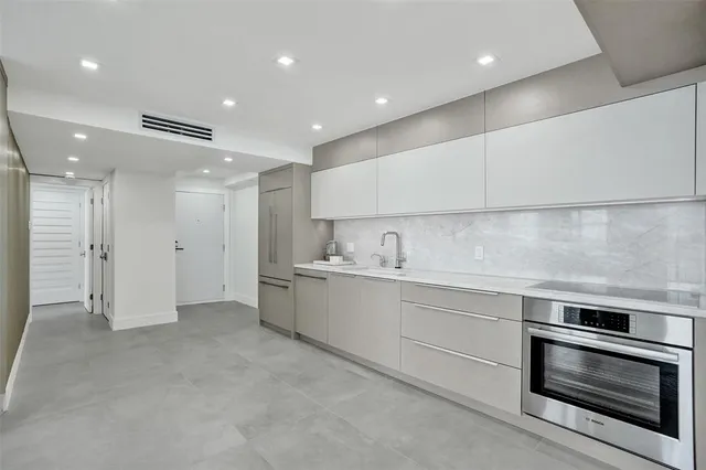 a large white kitchen with a refrigerator and white cabinets