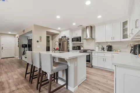 a kitchen with white cabinets stainless steel appliances and dining table