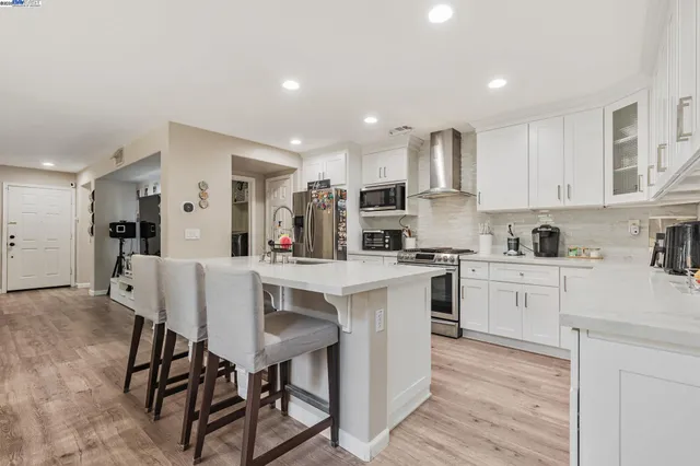 a kitchen with white cabinets stainless steel appliances and dining table