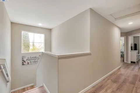 a view of hallway with window and wooden floor