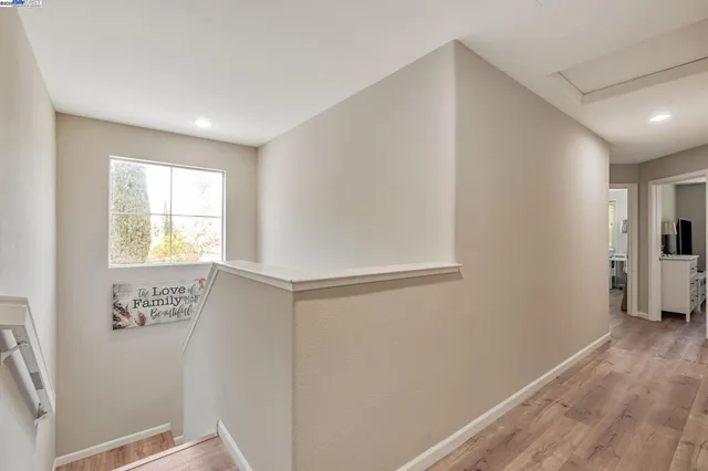 a view of hallway with window and wooden floor