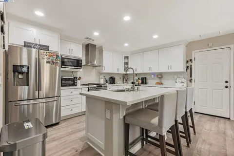 a kitchen with a refrigerator a sink and a stove top oven with wooden floor