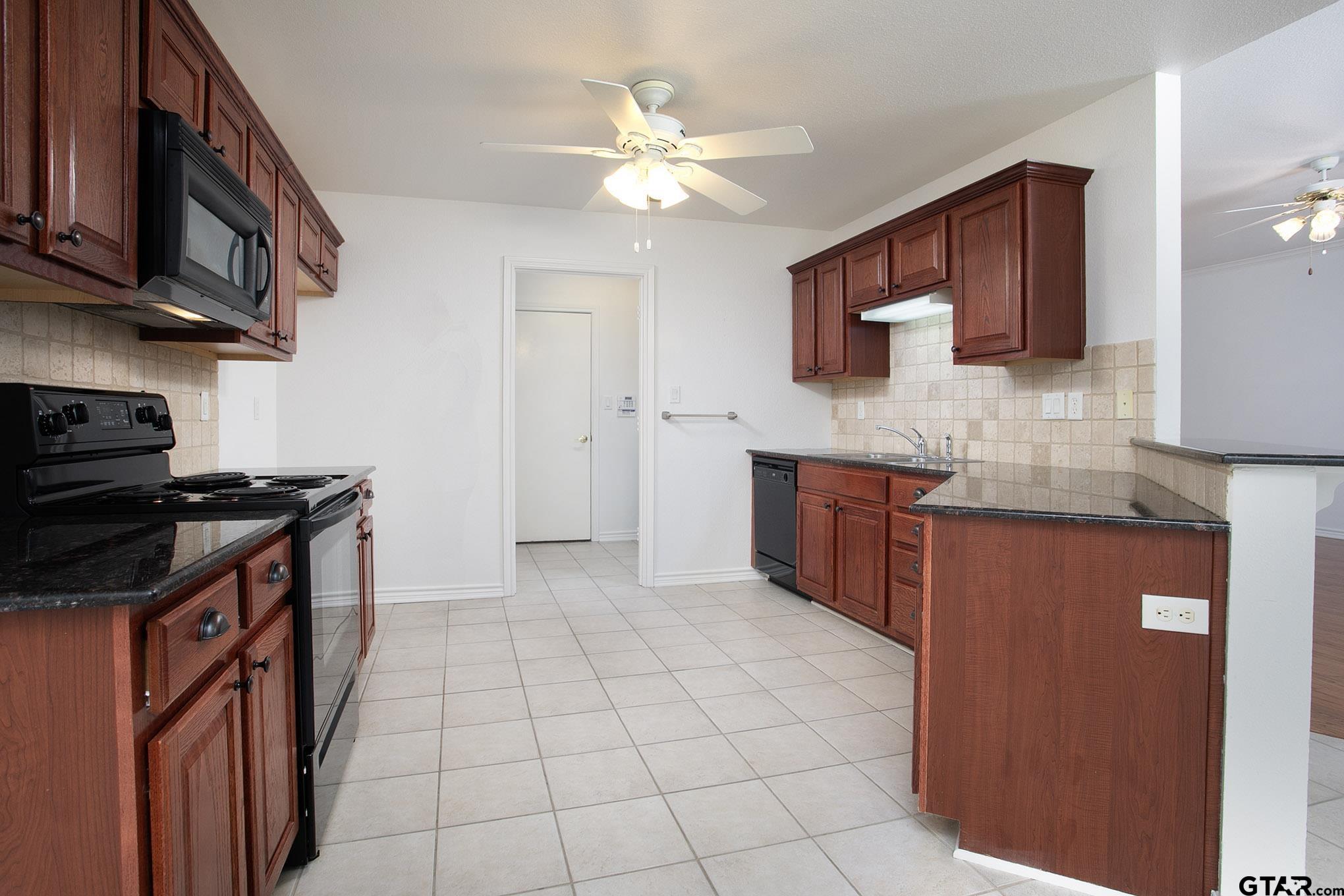 1521 Rice Road, Unit E105 Tyler, TX 75703 - Photo 11 of 32 a kitchen with stainless steel appliances granite countertop a stove a sink and a microwave