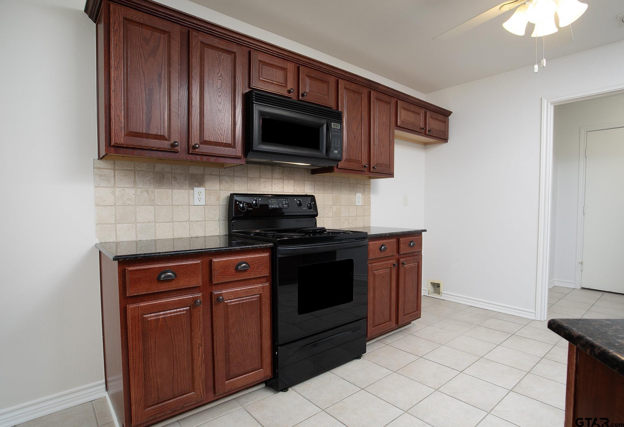 1521 Rice Road, Unit E105 Tyler, TX 75703 - Photo 12 of 32 a kitchen with stainless steel appliances granite countertop a stove microwave and sink