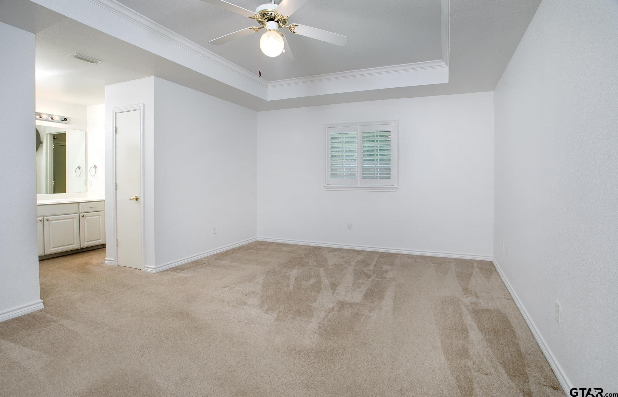 1521 Rice Road, Unit E105 Tyler, TX 75703 - Photo 17 of 32 an empty room with a ceiling fan and a window