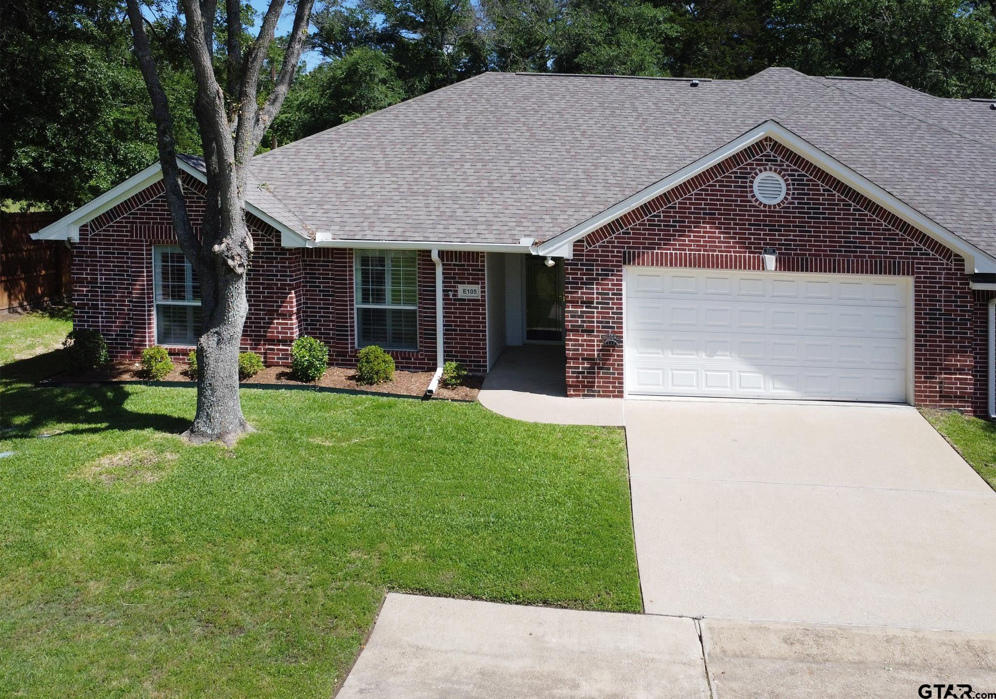 1521 Rice Road, Unit E105 Tyler, TX 75703 - Photo 2 of 32 a front view of a house with a garden and trees