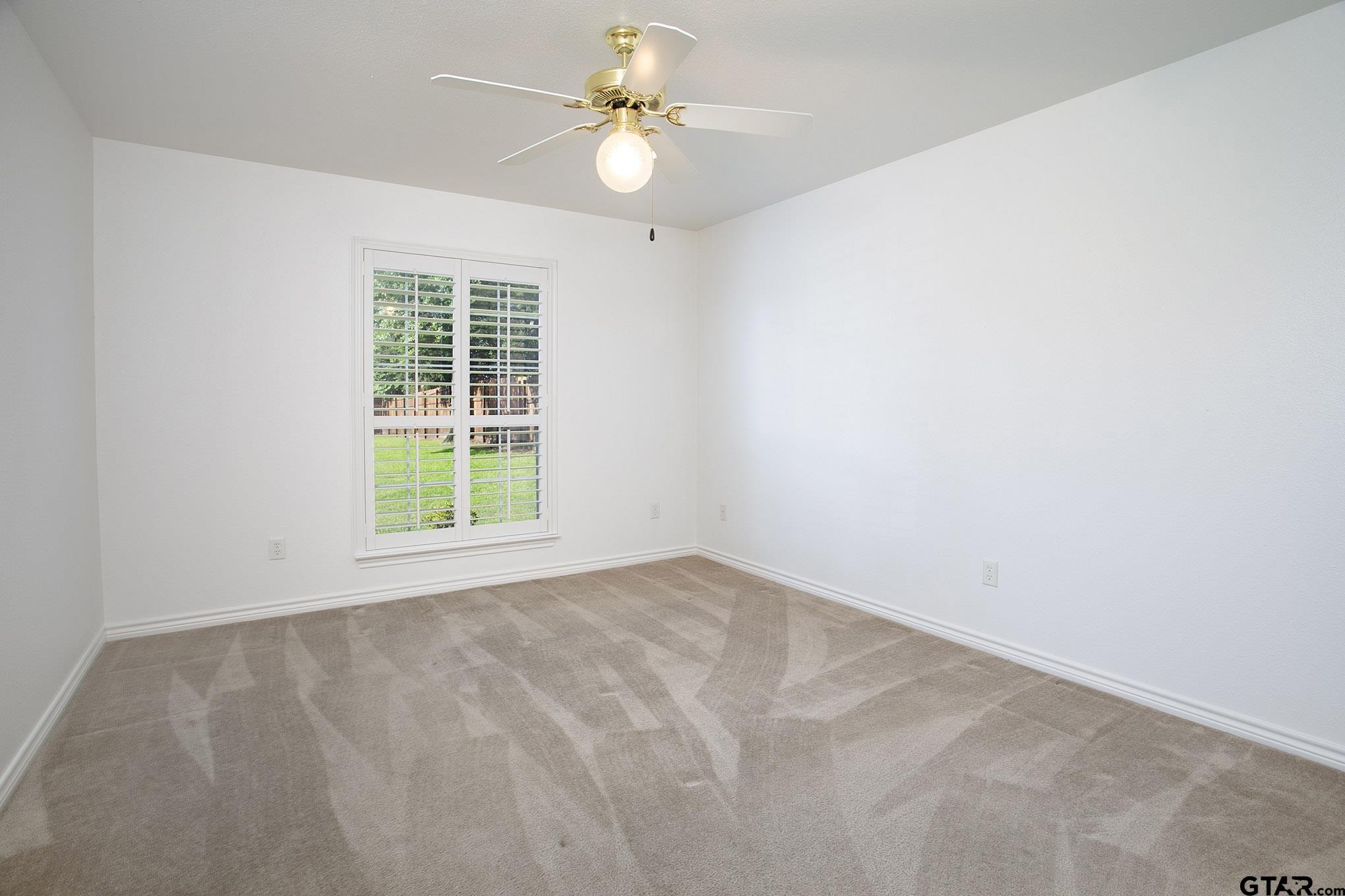 1521 Rice Road, Unit E105 Tyler, TX 75703 - Photo 21 of 32 an empty room with a window and a fan