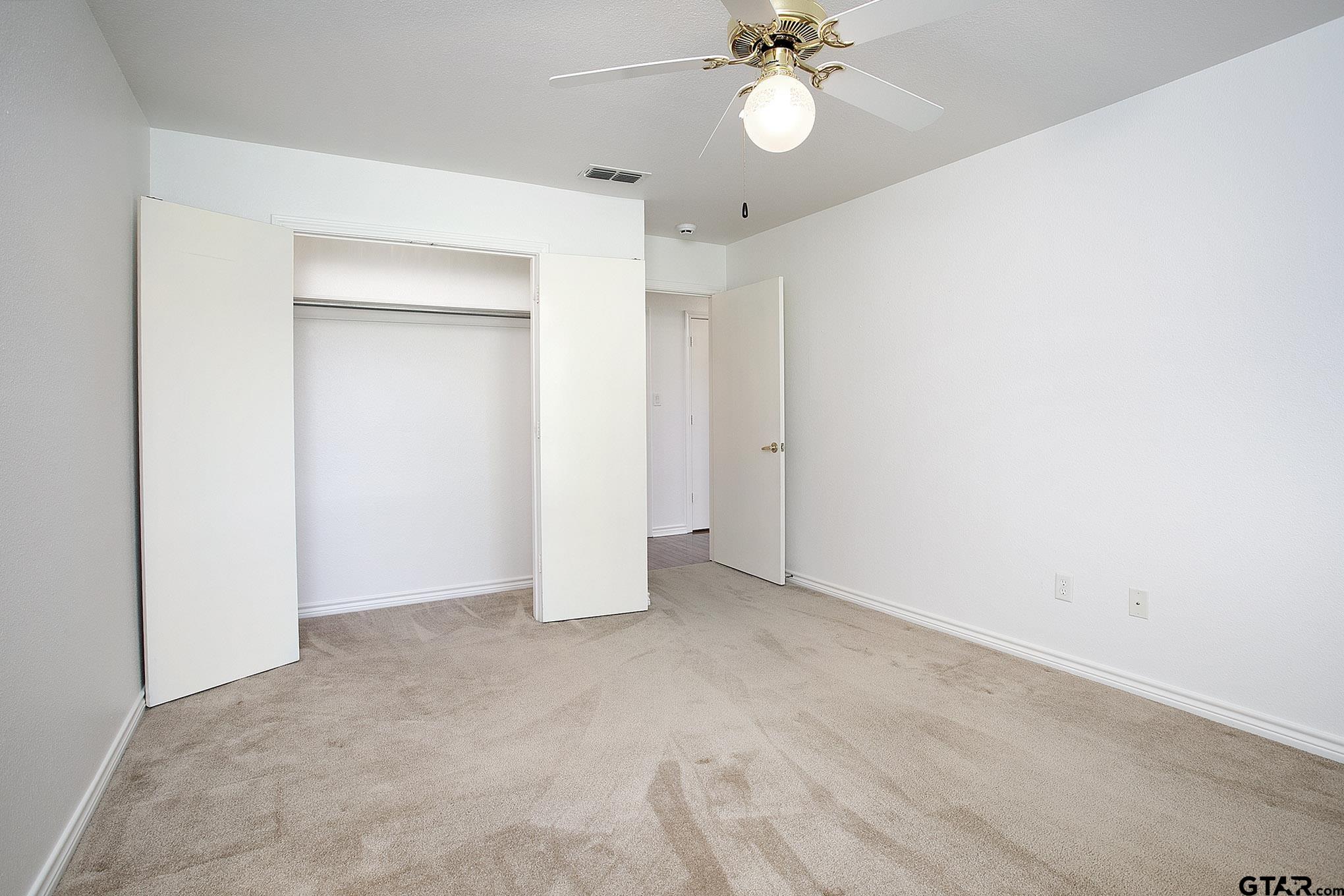 1521 Rice Road, Unit E105 Tyler, TX 75703 - Photo 22 of 32 an empty room with a chandelier fan and closet