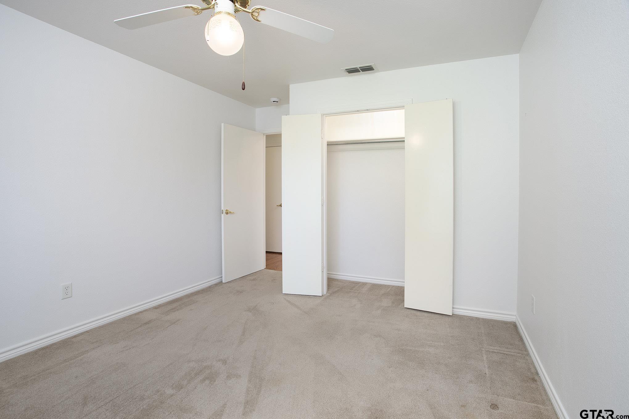 1521 Rice Road, Unit E105 Tyler, TX 75703 - Photo 24 of 32 an empty room with a chandelier fan and closet