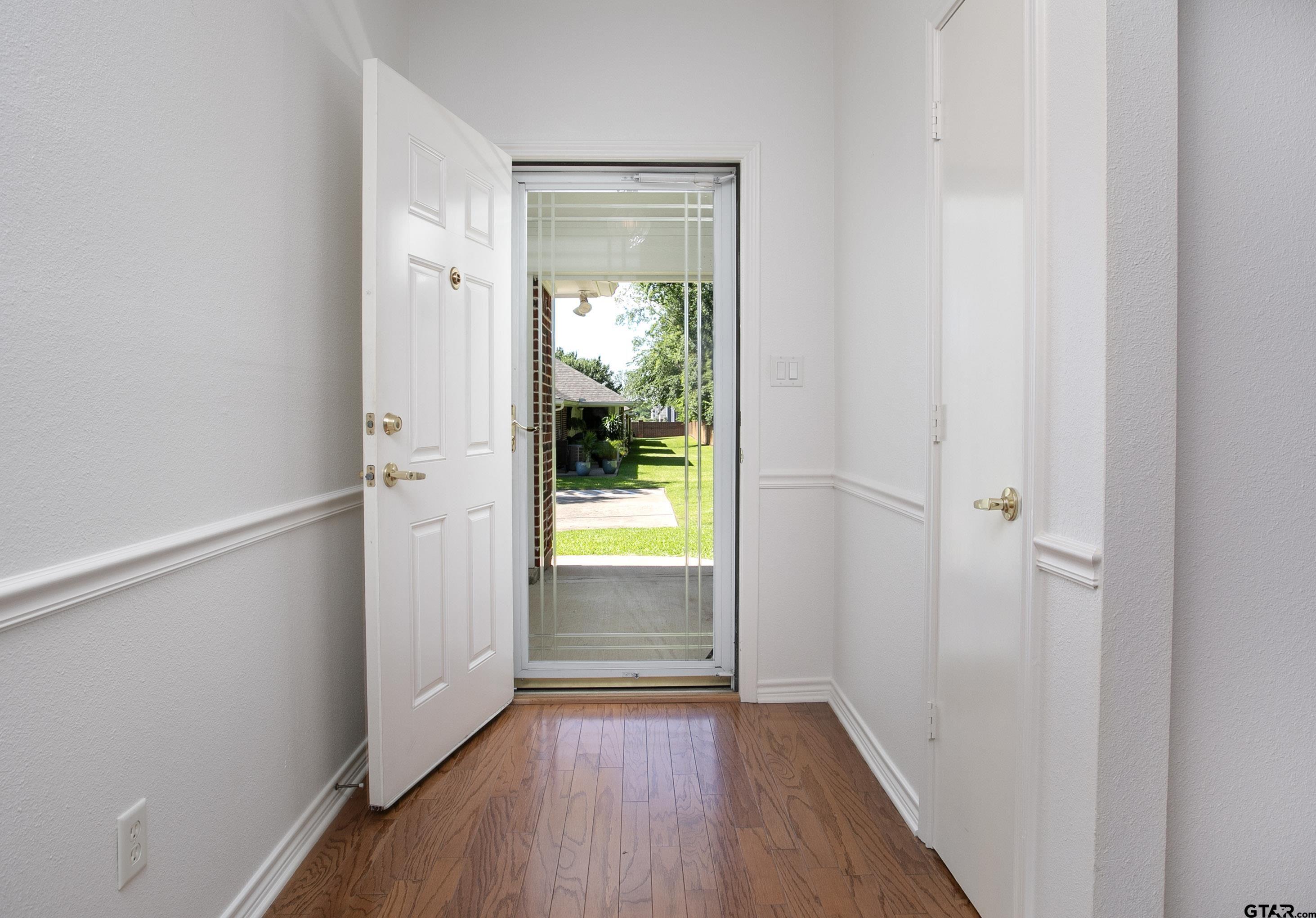 1521 Rice Road, Unit E105 Tyler, TX 75703 - Photo 6 of 32 a view of an empty room with wooden floor and a window